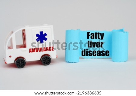 Medical concept. On a white surface, an ambulance and a blue paper sign with the inscription - Fatty liver disease
