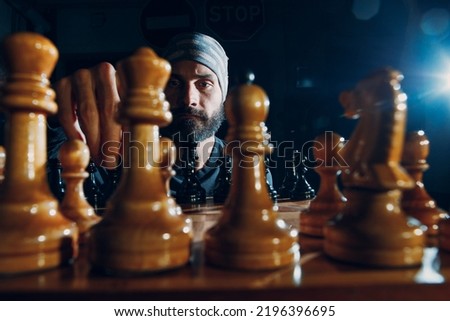 Young adult handsome man playing chess in dark. Chess figures and male face on board.