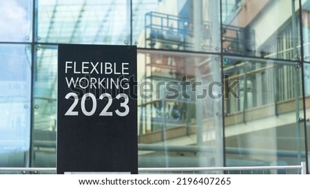Flexible Working 2023 on a city-center sign in front of a modern office building	
