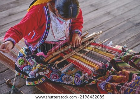 Indigenous woman showing traditional weaving technique and textile making in the Andes mountain range of South America in Peru, Selective focus. Royalty-Free Stock Photo #2196432085