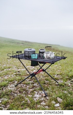 The concept of a set of utensils for camping in nature, breakfast for two in hiking conditions, a frame table made of mesh. High quality photo