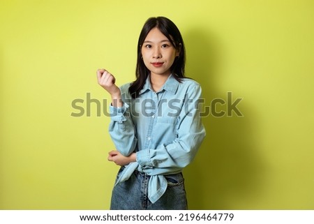 Japanese Millennial Lady Posing Looking At Camera Standing Over Yellow Studio Background, Wearing Casual Clothes. Modern Female Fashion And Beauty Concept