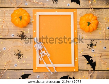 Wooden frame with pumpkin, skeleton, spiders and bats on a wooden background. A festive Halloween theme. Empty space for text.