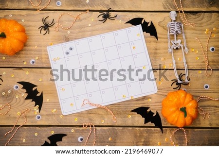 Pumpkins, skeletons, spiders and bats on a wooden background. Calendar or schedule. A festive Halloween theme. Empty space for text.