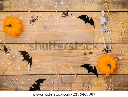 Pumpkins, skeletons, spiders and bats on a wooden background. A festive Halloween theme. Empty space for text.