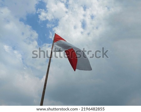 Indonesia's red and white flag flutters against the sky on a bamboo pole