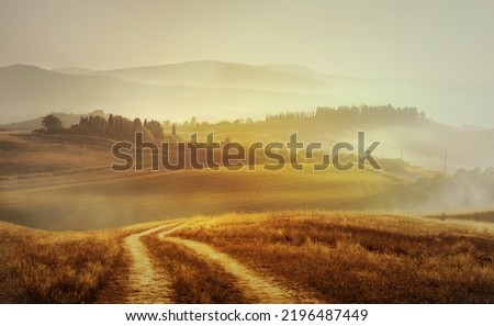 Autumn  rural landscape in retro style; Panorama of autumn field with dirt road and cloudy sky. 