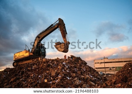 Building excavator with bucket work on concrete waste Royalty-Free Stock Photo #2196488103