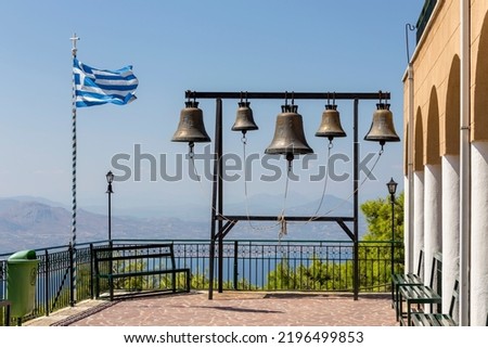 The bell tower and the flag develops against the background of the sea and the sky in the monastery on a sunny, summer day (Greece)