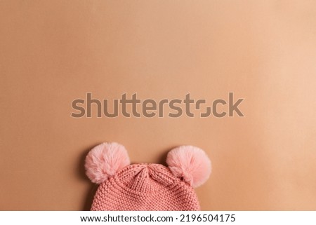 Children's pink hat on a brown background view from above. Minimalistic banner with space for the text of knitted things