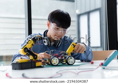 Asian teenager doing robot project in science classroom. technology of robotics programing and STEM education concept. Royalty-Free Stock Photo #2196504387