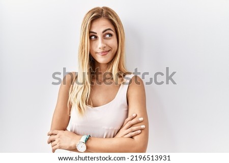 Blonde beautiful young woman standing over white isolated background smiling looking to the side and staring away thinking. 