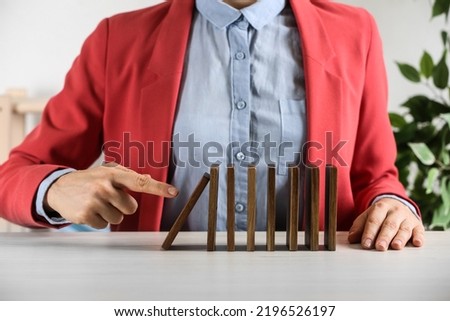 Woman causing chain reaction by pushing domino tile at table, closeup Royalty-Free Stock Photo #2196526197