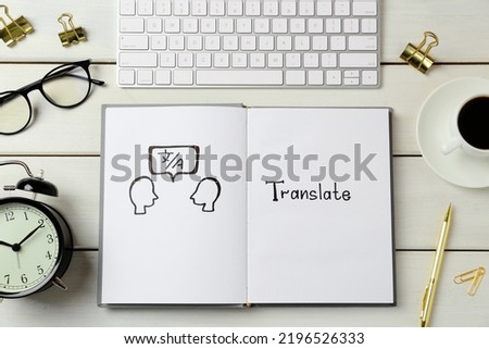 Flat lay composition with word Translate written in notebook, keyboard and eyeglasses on white wooden table