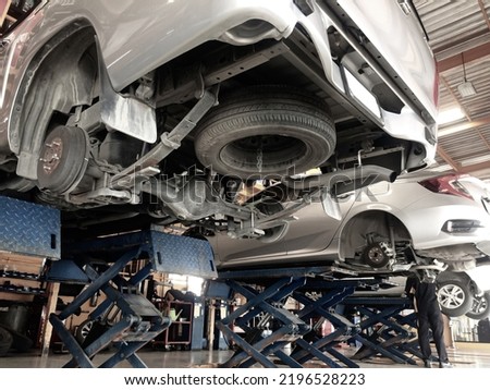 Pickup truck and sedan car in the process of changing wheels on the car lifts in a garage. Focus on the wheel hub. Royalty-Free Stock Photo #2196528223