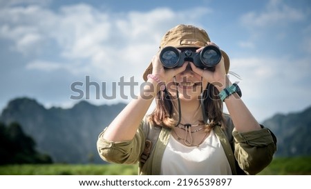 woman looking through binoculars on the hill woman in t-shirt with backpack