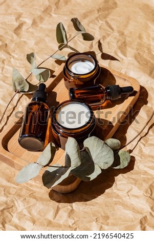 anti-aging collagen facial serum in dark glass bottle and face cream on wooden tray on craft paper background with eucalyptus branch. Natural Organic Cosmetic Beauty Concept Royalty-Free Stock Photo #2196540425