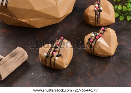 Chocolate with the shape of heart. Peanuts in the chocolate. Concept of love with Delicious heart shaped chocolate pictures. Chocolate with small wooden hammer. Chocolates on the black background. 