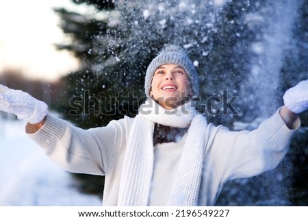 Portrait of happy beautiful girl, young joyful positive woman walking playing with snow, snowflakes, having fun outdoors in winter clothes, hat and scarf, smiling. Winter season, weather  Royalty-Free Stock Photo #2196549227