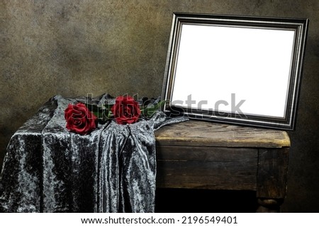 Empty wooden ornate picture frame photo with red roses flowers on wooden table with textile