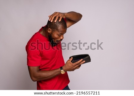 broke african man holding an empty wallet Royalty-Free Stock Photo #2196557211