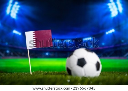 Qatar Mini Flag and football ball. Sport soccer Wallpaper. Football Stadium in night in Background