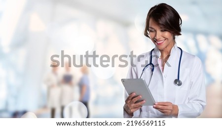 Smiling female doctor holding clipboard in her hand while standing at the clinic. Unrecognizable medical team standing at the background. Copy space. Royalty-Free Stock Photo #2196569115