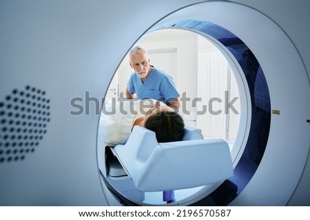 CT scan technologist overlooking patient in Computed Tomography scanner during preparation for procedure. Woman patient going into CT scanner Royalty-Free Stock Photo #2196570587