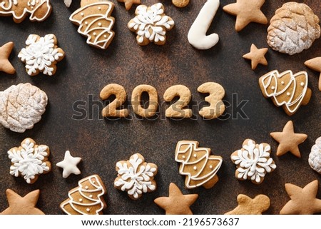Christmas holidays glazed homemade cookies and date 2023 from cookies on brown background. Happy New Year. View from above. Flat lay.