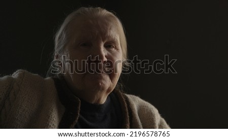 Senior woman sitting indoor with soft window light, wide photo