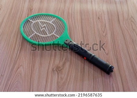 mosquito killing electric zapper racket green and white on wooden background isolated