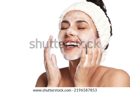 Beautiful woman applying facial cleansing foam on white background Royalty-Free Stock Photo #2196587853