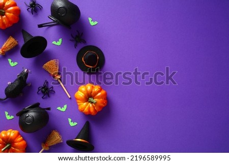 Happy Halloween holiday concept. Halloween background with pumpkins, bats, spiders, witch hats and brooms on purple table. Flat lay, top view, overhead. Halloween greeting card template.