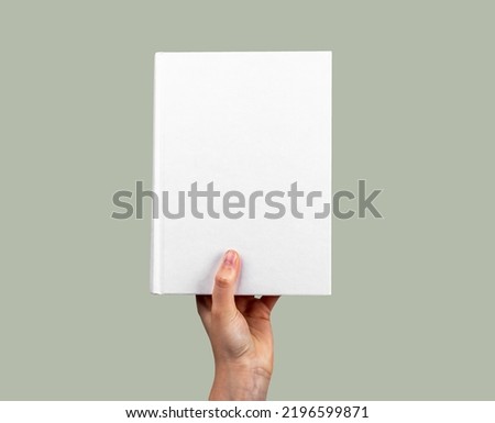 Hand holding closed book mockup with white cover. Novel, encyclopedia, code, Bible template. Reading hobby, study, learning new information concept. High quality photo Royalty-Free Stock Photo #2196599871