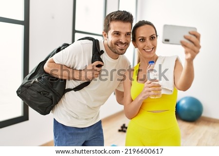 Young hispanic sporty couple making selfie by the smartphone at sport center.