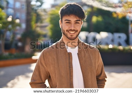 Young hispanic man smiling confident standing at park Royalty-Free Stock Photo #2196603037