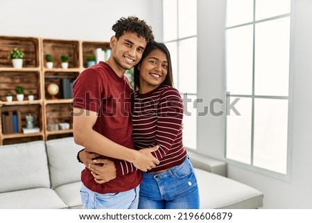 Young latin couple smiling happy and hugging standing at home.