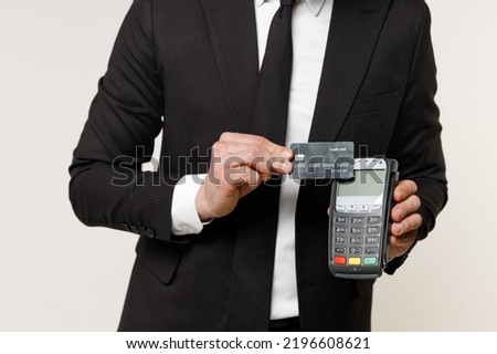 Close up cropped photo portrait shot young employee business man 20s in black suit shirt tie work in office hold wireless bank payment terminal acquire credit card payment isolated on white background