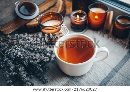 A cup of herbal tea with burning candles, aesthetically warm photo.