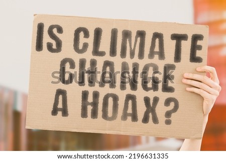 The question " Is climate change a hoax? " is on a banner in men's hands with blurred background. Planet. News. Warming. Weather. Results. World. Co2. Energy. Technology. Hot. Money. Pay. Myth. Tale Royalty-Free Stock Photo #2196631335
