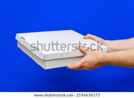 A man holds boxes in his hands on a blue background. Service delivery of goods. City delivery service.