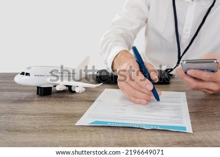 Closeup photo of young male traveller filling travel insurance form, studio, light gray background