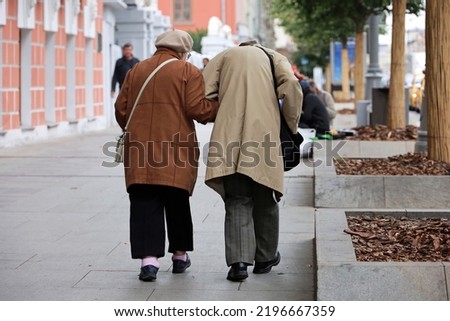Elderly man and woman walking down the autumn street, rear view. Old couple holding hands together, concept of old age Royalty-Free Stock Photo #2196667359