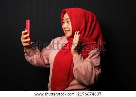 A woman with say hello gesture while having video calling. Happy expression isolated on black background.