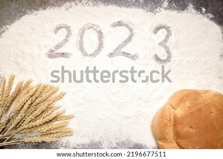 Number 2023 with ears of wheat and loaves of bread on flour. New Year and Christmas concept