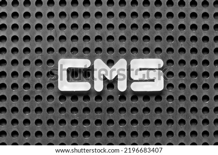 White alphabet letter in word CMS (Abbreviation of Content management system) on black pegboard background