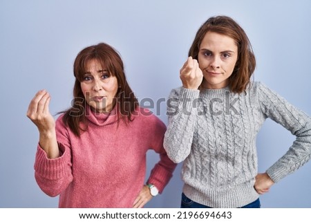 Mother and daughter standing over blue background doing italian gesture with hand and fingers confident expression 