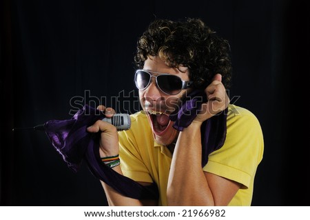 Portrait of a young man screaming with a microphone - isolated over black