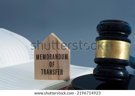Judge gavel with memorandum of transfer text on wooden house on white background.