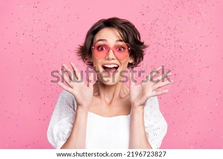 Photo of impressed funny girl dressed white top heart eyewear rising arms open mouth isolated pink color background